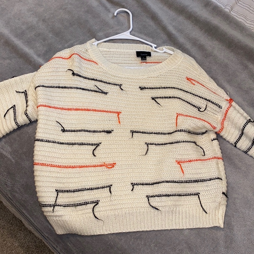 Cream sweater with orange and black details.